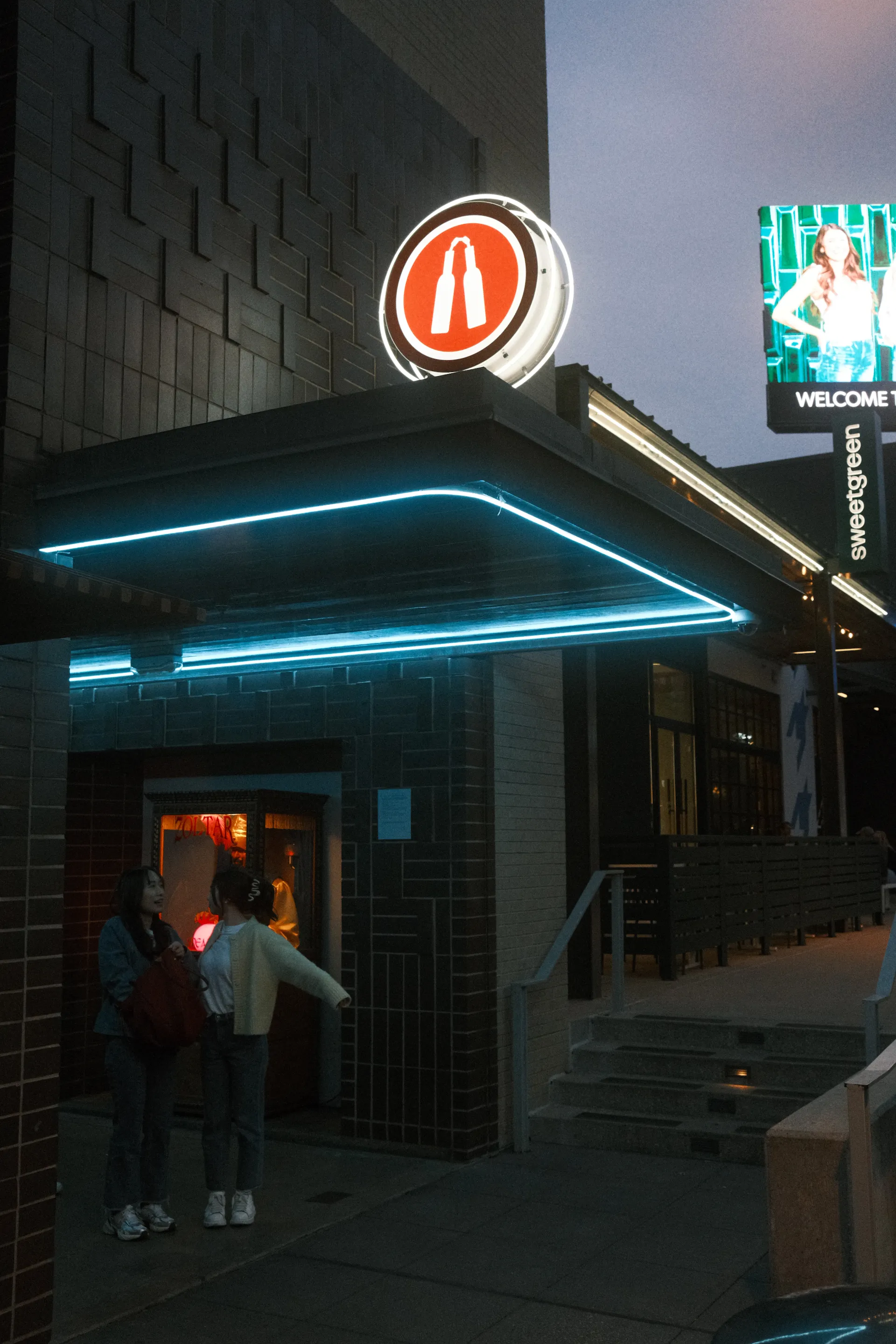 Two girls standing outside of a bar