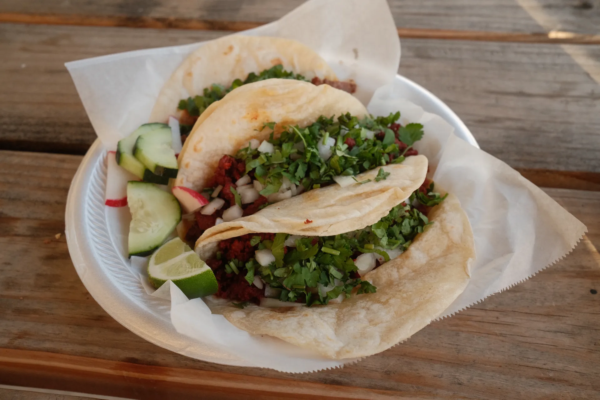 three tacos on a wooden picnic table